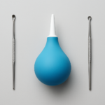 Blue ear syringe and metal ear cleaning tools on a gray surface