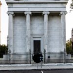 A classical building with pillars and a gated entrance.