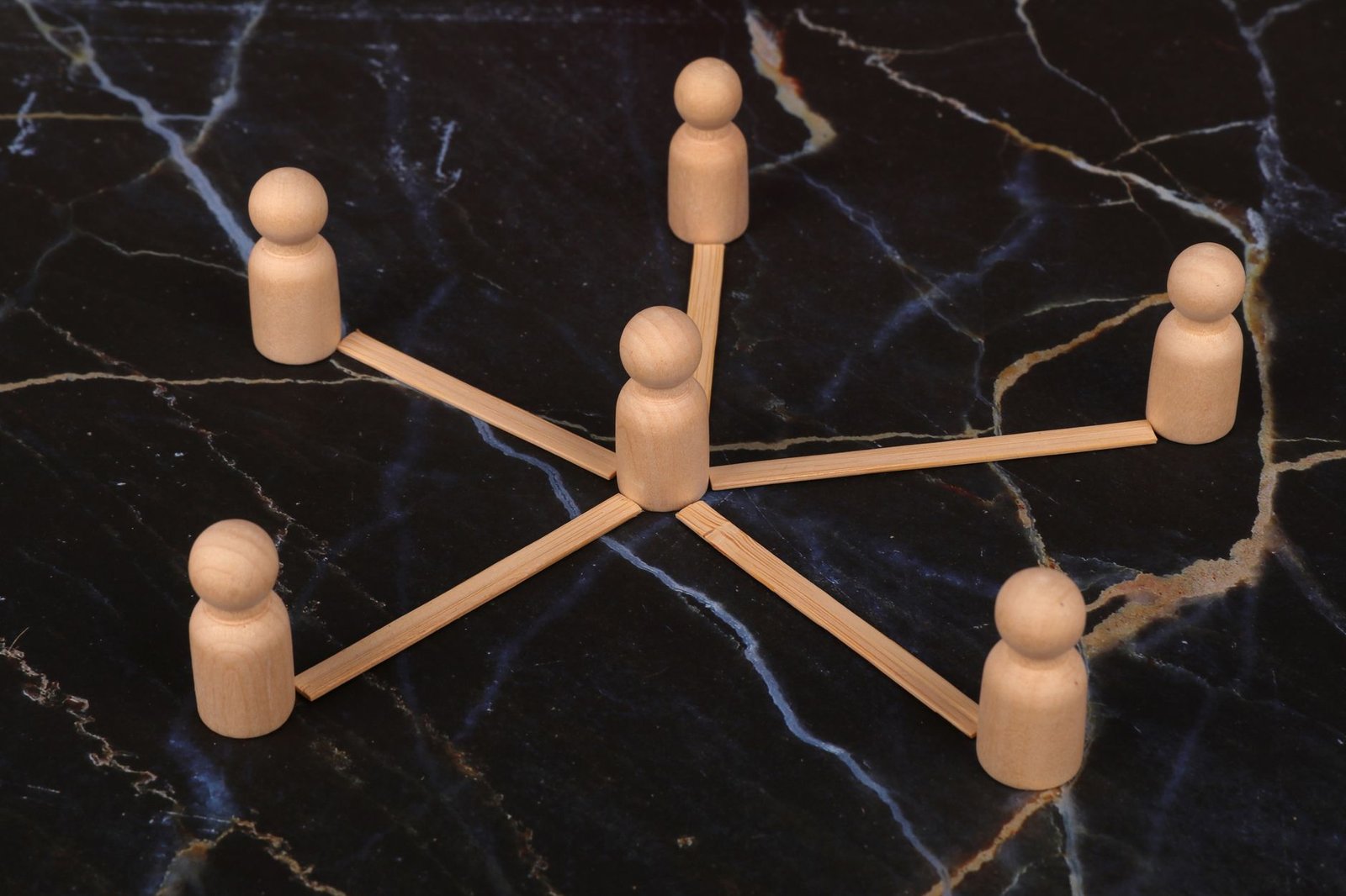 Wooden figurines arranged in a circular formation on a dark surface